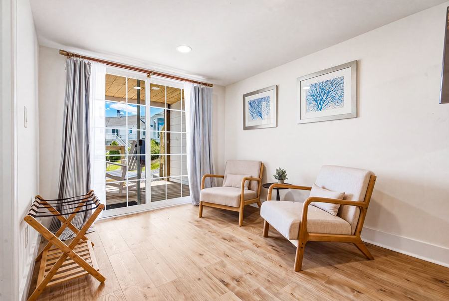 Room 6 sitting area with two chairs, balcony doors, and natural light.