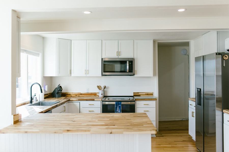 Bright guest kitchen with white cabinets, modern appliances, and a large countertop