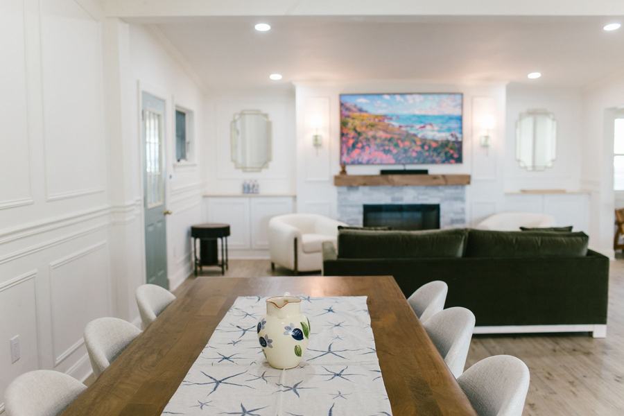 Bright dining and living room with large table, sofa seating, and fireplace.